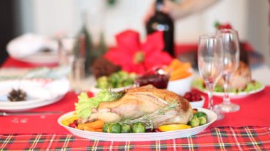 Şükran Günü ya da Noel yemeği için servis edilen masa. Arka plandan şampanya döken bir kadın. Ön planda kızarmış hindi dolması. Geleneksel kutlama tatili