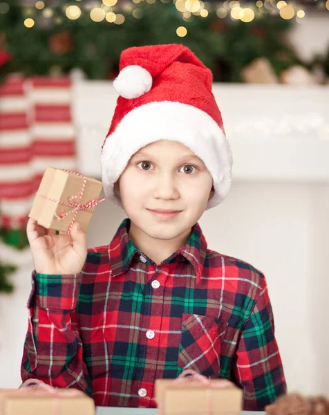 Zabawny chłopiec w czapce Santa trzymając pudełko prezentów. — Zdjęcie stockowe