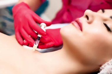 Kadın boynuna güzellik iğnesi yaparken yatakta yatıyor. Yüz bakımı. Güzellik konsepti.