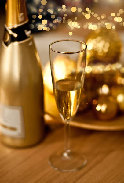 Świąteczne nakrycie stołu z dekoracjami wakacyjnymi w kolorze złotym. Święto Nowego Roku. Butelka i kieliszek szampana.. — Zdjęcie stockowe