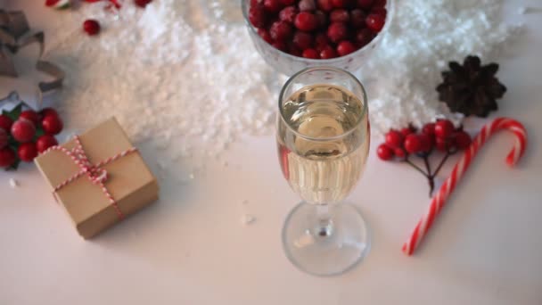 女人的手拿一杯香槟。背景是覆盆子和圣诞装饰品.圣诞及新年概念. — 图库视频影像