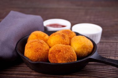 Demir tavada patates köftesi ve sos var.