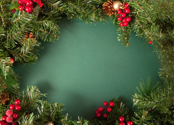 Décoration de cadre de Noël avec des baies, des cônes et des branches d'arbre de Noël sur le fond vert. Espace de copie. — Photo