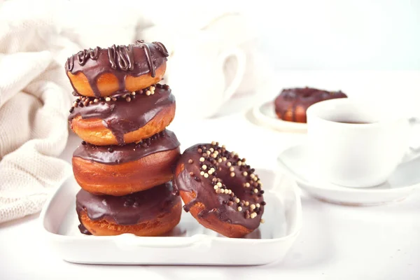 Stack of doughnut on the plate glazed with chocolate cream or icing with cup of tea on the background. Breakfast concept. — Stock Photo, Image