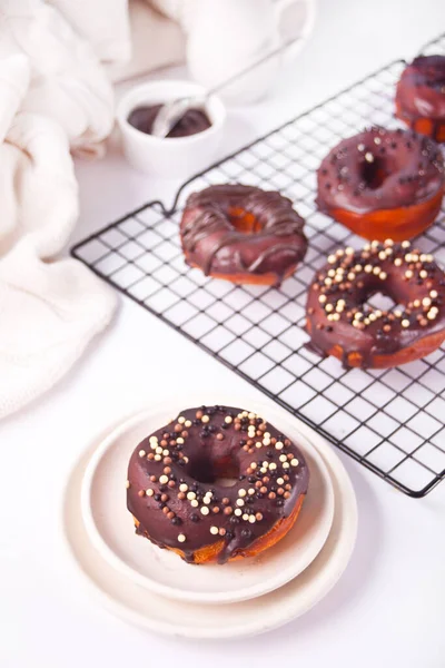 Doughnut on the baking rack and on the plate glazed with chocolate cream or icing. Breakfast concept. — Stock Photo, Image