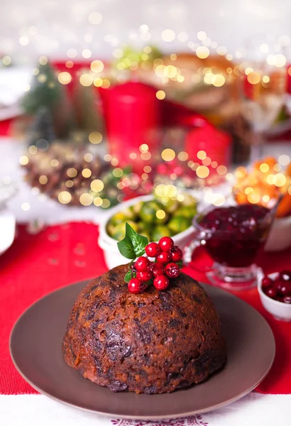 Pudín de Navidad tradicional con acebo en la parte superior en una cena de Navidad. — Foto de Stock