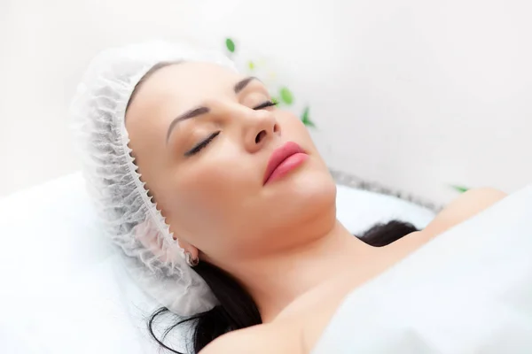 Mujer acostada en la cama mientras recibe inyección de belleza en el cuello. Tratamientos faciales. Concepto de belleza. —  Fotos de Stock