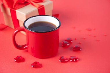 Kırmızı arka planda bir kupa kahve ve hediye kutusu.