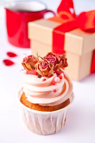 Valentines cupcake cream cheese frosting decorated with dry rose flowers, mug of coffee and gift box on the background. — Stock Photo, Image