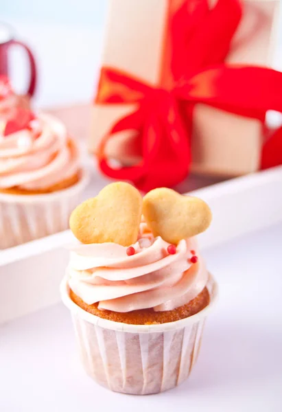 Valentine cupcakes creme queijo cobertura decorada com biscoitos em forma de coração e caixa de presente no fundo. — Fotografia de Stock