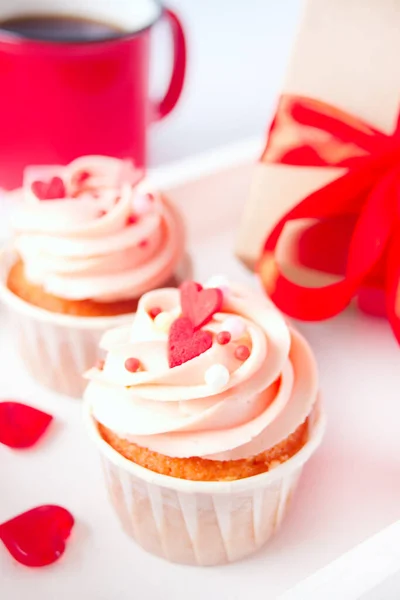 San Valentín cupcake crema de queso glaseado decorado con caramelos del corazón, taza de café y caja de regalo en el fondo. — Foto de Stock