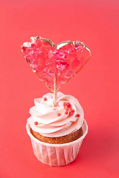 Valentine cupcake cream cheese frosting decorado com pirulitos de doces no fundo vermelho. — Fotografia de Stock