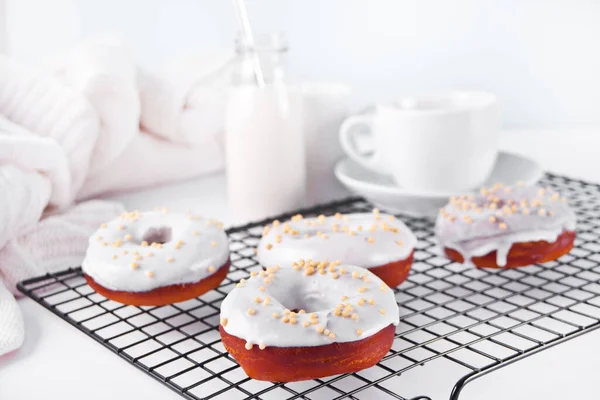 Donuts na cremalheira vidros creme de chocolate branco ou gelo e garrafa com leite no fundo. — Fotografia de Stock