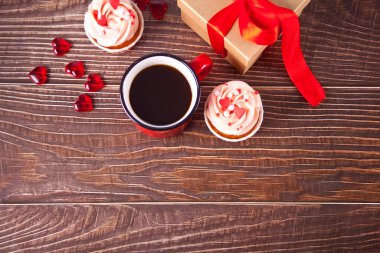 Sevgililer Günü kekleri krem peynirli krem peynir, kalp şekeriyle süslenmiş, bir kupa kahve ve hediye paketi. Sevgililer Günü konsepti. Uzayı kopyala Üst görünüm.