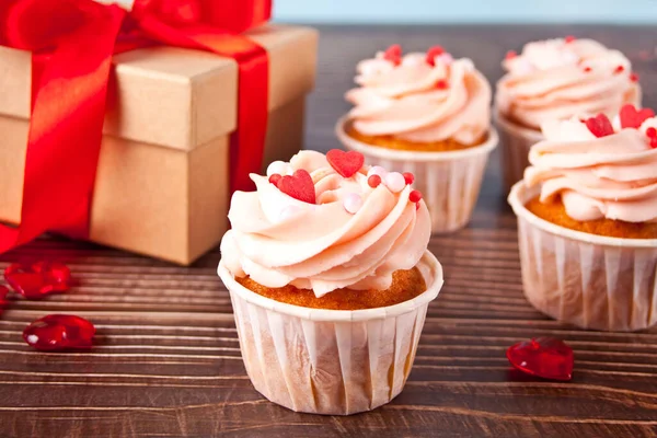 Cupcakes de San Valentín crema de queso glaseado decorado con caramelos del corazón y caja de regalo en el fondo de madera. —  Fotos de Stock