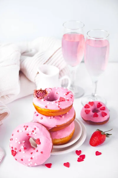 Verres de vin rose ou champagne et beignets roses sur le support à pâtisserie. Concept Saint-Valentin. — Photo