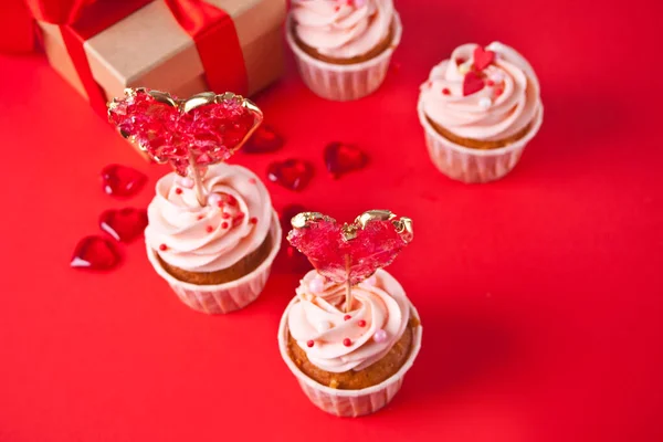 Valentine cupcake cream cheese frosting decorado com pirulito coração doce e caixa de presente no fundo. — Fotografia de Stock
