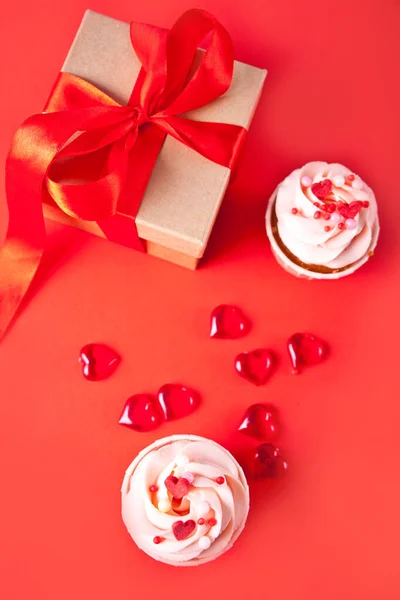 Valentine cupcakes creme de queijo cobertura decorada com doces do coração e caixa de presente no fundo vermelho. Vista superior. — Fotografia de Stock