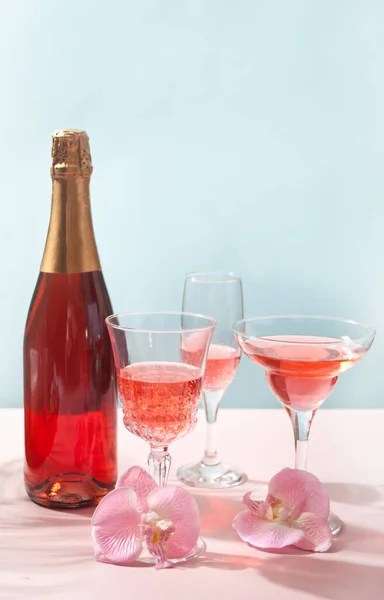 Zomer tropische roze cocktail wijn champagne in een andere bril met fles versierd roze orchidee bloemen — Stockfoto