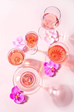 Farklı bardaklarda, pembe orkide çiçekleriyle süslenmiş tropikal bir kokteyl. Üst görünüm.