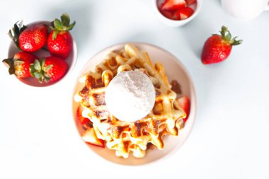 Freshly homemade baked waffles with strawberries, honey and ice cream. Top view.