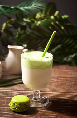 Dalgona Matcha Latte, kremalı kibrit yeşil çay, arka planda bitki var.