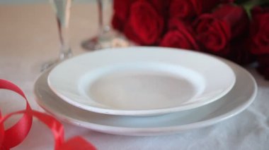 Güllü, tabaklı ve gözlüklü iki kişilik romantik restoran masası..