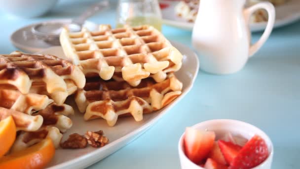 Desayuno de la mañana. Gofres recién hechos al horno con fresas y miel. Mano humana poner un plato con fresa — Vídeos de Stock