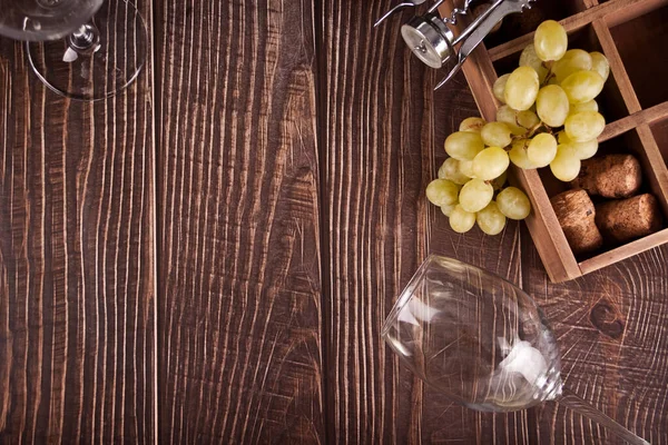Empty glasses of white grape wine with grapes and wooden box on the background