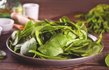 Koyu ahşap arka plandaki tabakta ıspanak var.