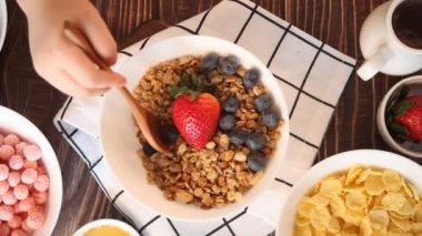 Sağlıklı kahvaltı. Çocuk eli kaşık granola ile karıştırılır, taze böğürtlen ile müsli.