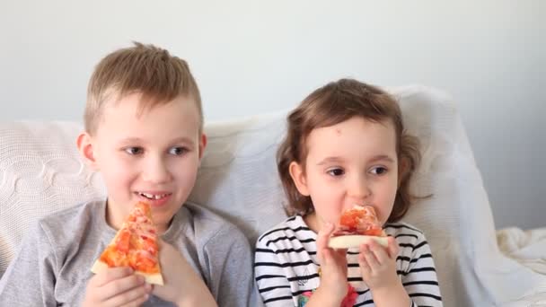 Linda niña y niño comiendo pizza en casa — Vídeos de Stock