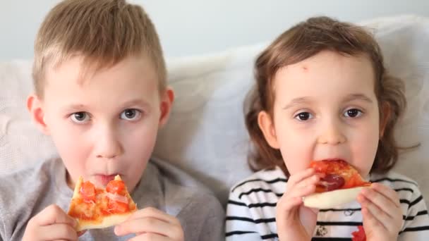 Süße kleine Mädchen und Jungen, die zu Hause Pizza essen — Stockvideo