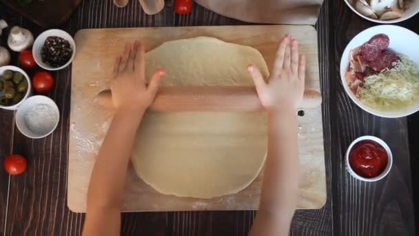 Kind rolt het deeg het maken van pizza in de thuiskeuken. Bovenaanzicht. — Stockvideo