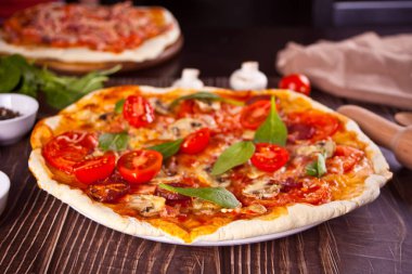 Pepperoni sosisli ev yapımı pizza, pastırmalı ıspanak ve arka planda malzemeler..