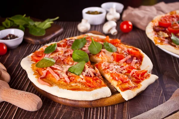 Pizza casera con salchicha de pepperoni, tocino decorado con espinacas e ingredientes en el fondo. — Foto de Stock