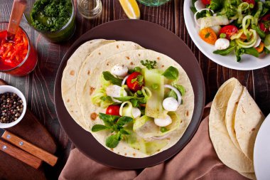 Meksika usulü vejetaryen tortilla dürümü. Yemek masasında sebze var.