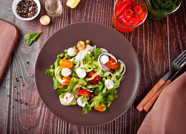 Sallad av färska körsbärstomater, mozzarella, basilika, rädisor och andra grönsaker på middagsbordet — Stockfoto