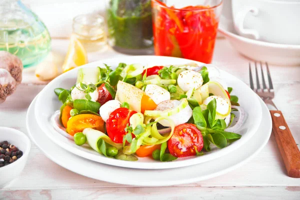 Sallad av färska körsbärstomater, mozzarella, basilika, rädisor och andra grönsaker på middagsbordet — Stockfoto