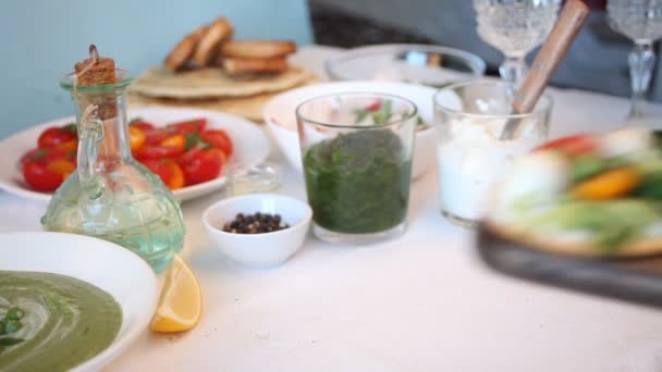 Женская рука положила режущую доску с круглыми хлебными тостами с зеленью и овощами. Концепция здорового питания. — стоковое видео
