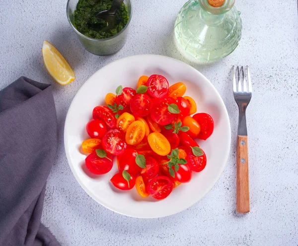 Sallader av färska körsbärstomater, mozzarella, basilika och andra grönsaker på middagsbordet — Stockfoto