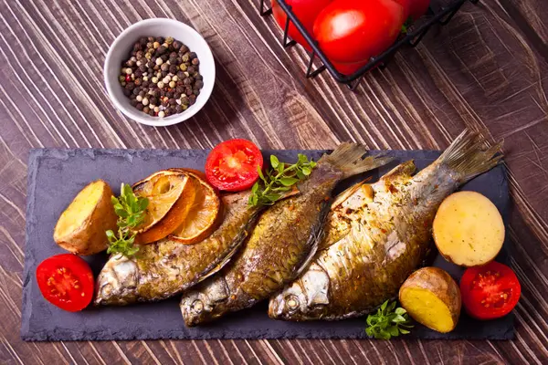 Pescado a la parrilla en plato con limón y verduras —  Fotos de Stock