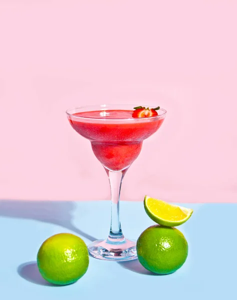 Cold strawberry margarita or daiquiri cocktail with lime and rum.