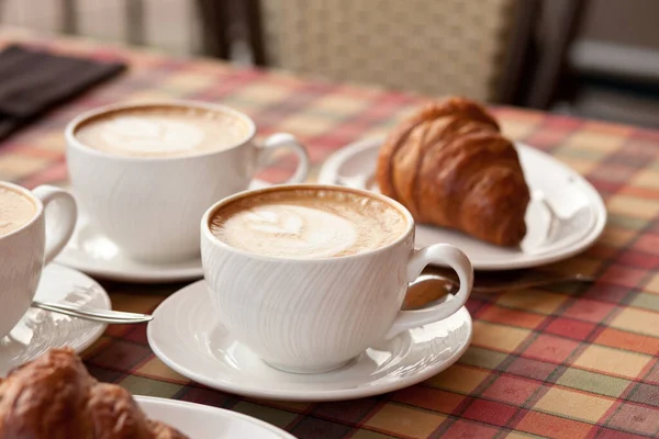 Cups of cappuccino coffee with croissant in a cafe — Stock Photo, Image