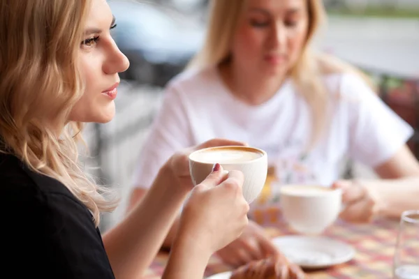 Jovem mulher bebendo um café em um terraço com amigos — Fotografia de Stock