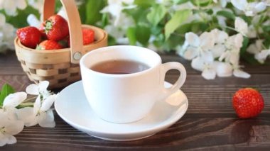 Kadın, çay bardağını beyaz elma çiçeğiyle süslüyor. Bahar konsepti.