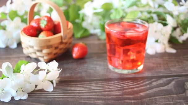 Γυναίκα χέρι θέσει ένα ποτήρι φράουλα κρύο αναψυκτικό λεμονάδα με παγάκι τραπέζι. Ανοιξιάτικη. — Αρχείο Βίντεο