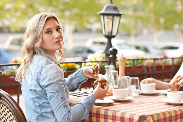 Jovem bebendo um café com croissant em um terraço com amigos — Fotografia de Stock
