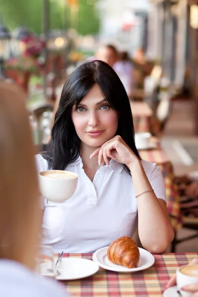Mulher morena sorridente no café bebendo café com croissant. Conceito de comunicação e amizade. — Fotografia de Stock