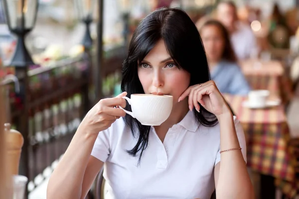 Mulher morena sorridente no café bebendo café com croissant. Conceito de comunicação e amizade. — Fotografia de Stock